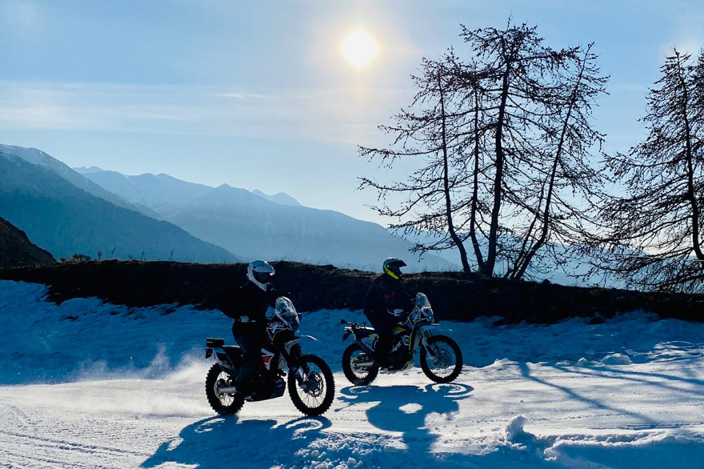 moto sur la neige derriere un couche de soleil